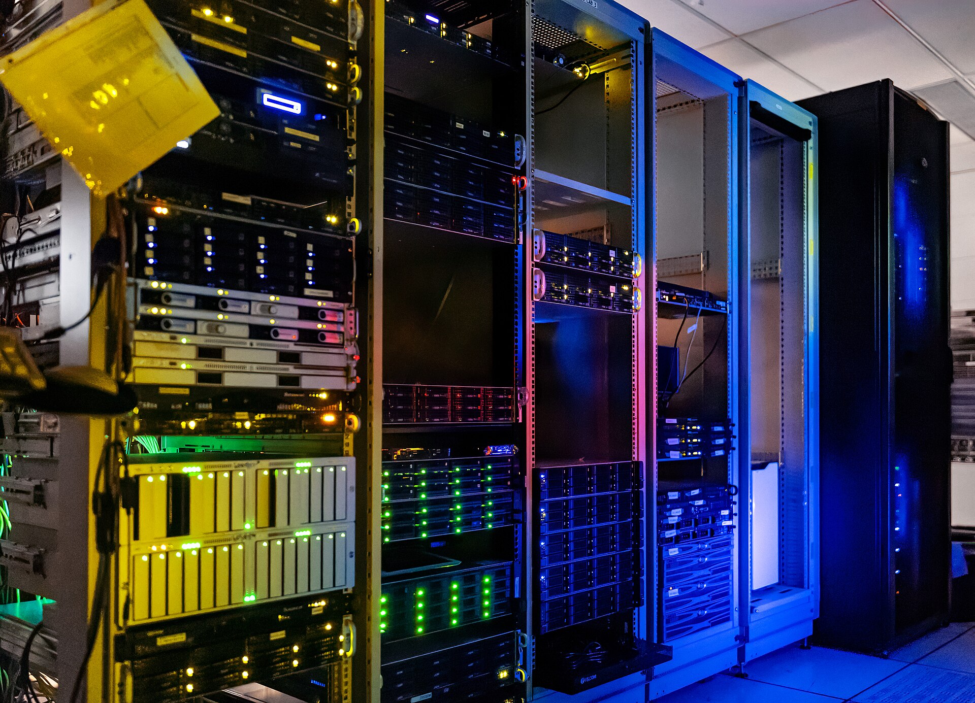Server racks lit in yellow, green and blue inside a data centre